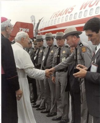 Pope John Paul II shaking the cands of a line of Troopers protecting him.