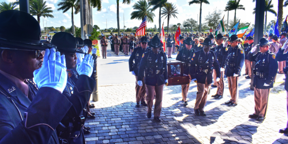 Troopers salute as Trooper Finks urn is carried by.